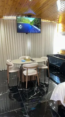 a table and chairs with a television on a wall at Akwakh Al-Kanz Huts Ajloun Jor in Ajloun