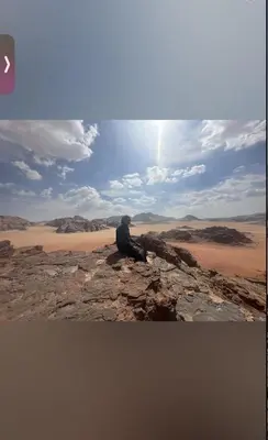 a man sitting on a rock in the desert at Wadi Rum, Mars Cave in Wadi Rum