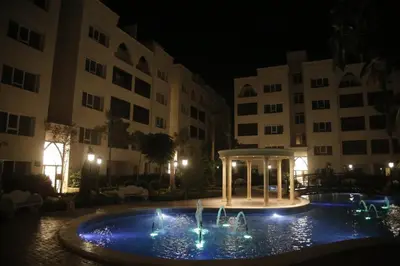 a pool in front of a building at night at saraya stays premium in Amman