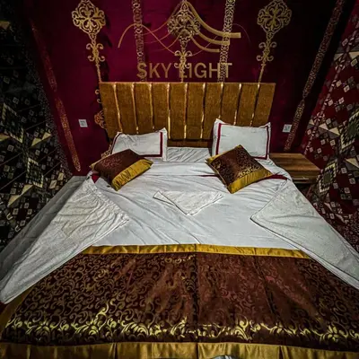 a bedroom with a large bed with golditures at Skylight Wadi Rum Camp in Disah