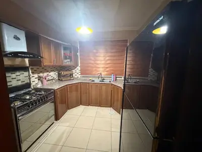 a kitchen with wooden cabinets and a sink and a stove at 3 bedroom cozy apartment prime location in Irbid in Irbid
