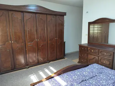 a bedroom with a large wooden bed and a dresser at Cozy 3 bed-2 bath furnished apartment in Amman