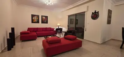 a living room with a red couch and chairs at شقة مفروشة فاخرة in Amman