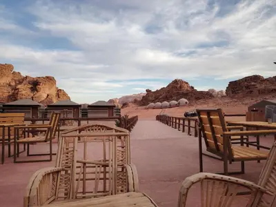 a row of wooden chairs and tables in the desert at Silent Dunes Camp in Disah