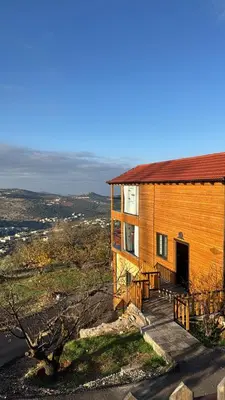 a large wooden house with a porch on a hill at Akwakh Al-Kanz اكواخ الكنز عجلون in Ajloun