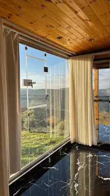 a room with a large window with a view at Akwakh Al-Kanz اكواخ الكنز عجلون in Ajloun