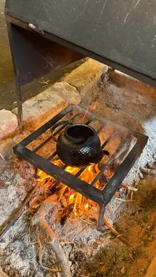 a pot on top of a stove with fire at Your Bedouin family home in Disah
