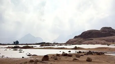 a group of rocks on a beach with mountains in the background at Your Bedouin family home in Disah