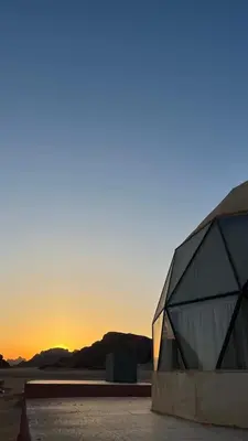 a building in the desert with the sunset in the background at Wadi rum camp in Wadi Rum