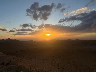 a sunset in the desert with the sun setting at Salem Guesthouse Experience in Al Ḩayy