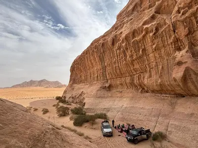 a group of people standing next to vehicles in the desert at Wadi Rum Luxury Trend in Wadi Rum