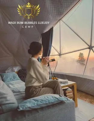 a woman sitting on a bed in a tent at WADI RUM BUBBLES lUXURY CAMP in Disah