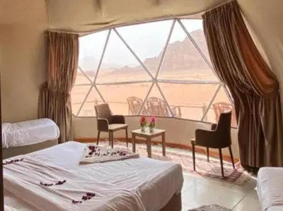 a bedroom with a bed and a large window at Wadi Rum Nada Camp in Wadi Rum