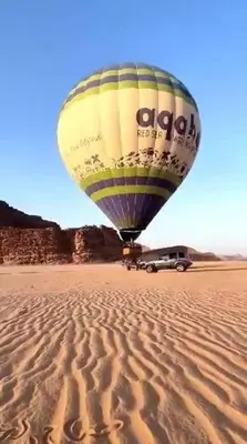 a hot air balloon flying over a desert at Wadi Rum Nada Camp in Wadi Rum