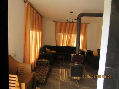 a living room with a black couch and orange curtains at اكواخ الملول عجلون 2 in Ajloun