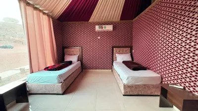 two beds in a room with a red wall at Hello Desert Camp & Tour