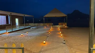a boardwalk with candles in the sand at night at Wadi Rum -Lekshary Hamza 55 in Wadi Rum