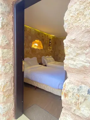 a bedroom with two beds in a stone wall at Petra Gateway Guest Room in Wadi Musa