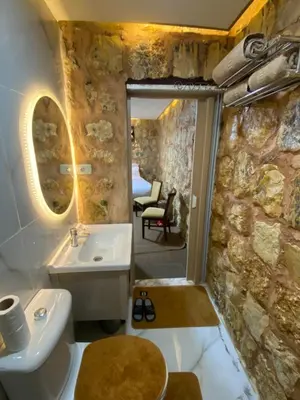 a bathroom with a sink and a stone wall at Petra Gateway Guest Room in Wadi Musa