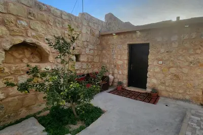 a stone building with a door and a tree at Petra Gateway Guest Room in Wadi Musa