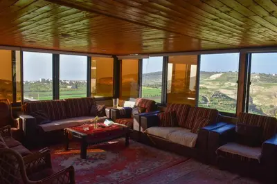 a living room with couches and a table and windows at Um Al Namel Villa & Chalet