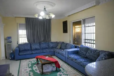 a living room with a blue couch and a table at Um Al Namel Villa & Chalet