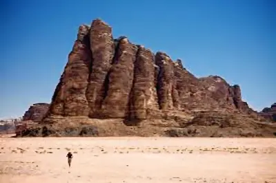 a person standing in front of a large rock formation at Isabella Desert Camp & Tour in Wadi Rum