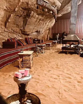a room in a cave with tables and a piano at Isabella Desert Camp & Tour in Wadi Rum