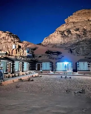 a building in front of a mountain at night at Isabella Desert Camp & Tour in Wadi Rum