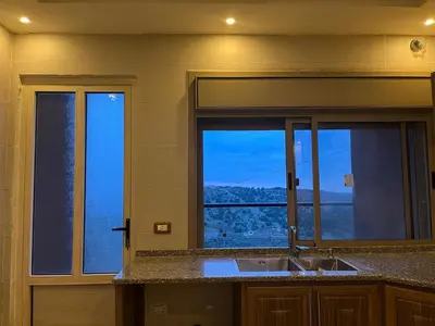 a kitchen with a sink and a window with a view at شقة للإيجار في راس منيف - عجلون in Ajloun
