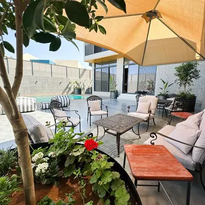 a patio with chairs and tables and an umbrella at Haifa Villa by Seahorse in Sowayma