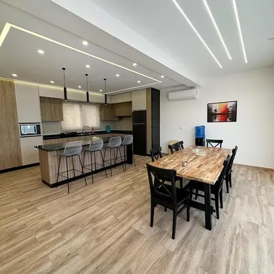 a room with a table and chairs and a kitchen at La Mer Villa by Seahorse in Al Rama