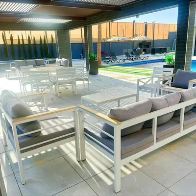 a patio with white tables and chairs and a pool at La Mer Villa by Seahorse in Al Rama