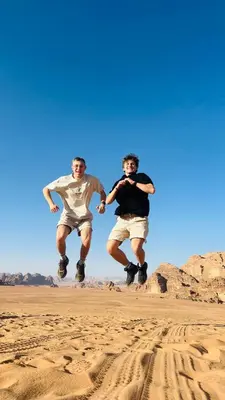 two men jumping in the sand in the desert at Wadi Rum Starfield Retreat in Wadi Rum