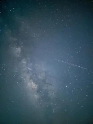 a plane is flying in the night sky at Wadi Rum Starfield Retreat in Wadi Rum