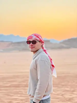 a man wearing sunglasses and a scarf standing in the desert at Wadi Rum Starfield Retreat in Wadi Rum
