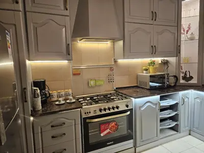 a kitchen with white cabinets and a stove top oven at شقة فاخرة في دير غبار in Amman