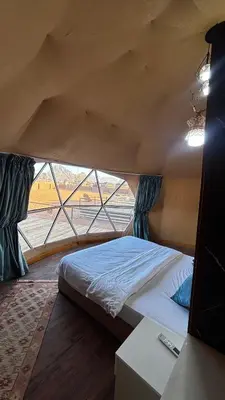 a bed in a room with a large window at The Red Rock Camp in Wadi Rum