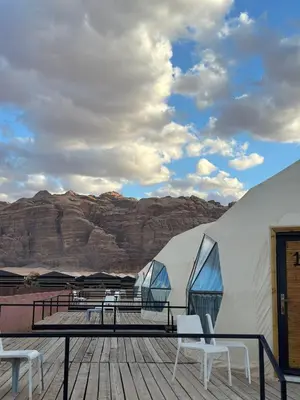 a couple of tents with tables and chairs on a deck at The Red Rock Camp in Wadi Rum