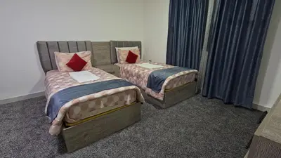 two beds sitting next to each other in a room at Masaya Al Deyar Apartments in Amman