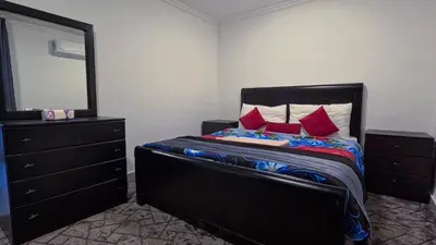 a bedroom with a bed with a dresser and a mirror at Masaya Al Deyar Apartments in Amman