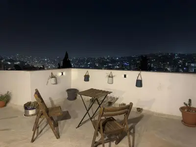 two chairs and a table on a rooftop at night at Modern Loft Studio Panoramic Views And Smart Design in Amman
