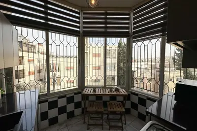 a room with a table and chairs in front of windows at Modern Loft Studio Panoramic Views And Smart Design in Amman