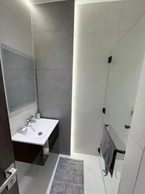 a white bathroom with a sink and a shower at Luxury 3-Bedroom Apartment in Amman