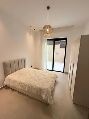 a white bedroom with a bed and a large window at Luxury 3-Bedroom Apartment in Amman