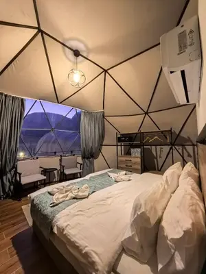 a bedroom with a large bed with a large window at Wadi rum bubble camp in Wadi Musa