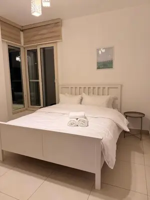 a bedroom with a white bed with two towels on it at 2 BR 100 sqm Modern Apt Abdoun in Amman