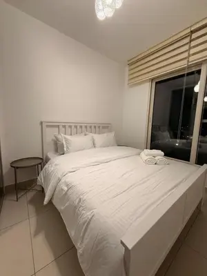 a white bed in a white bedroom with a window at 2 BR 100 sqm Modern Apt Abdoun in Amman