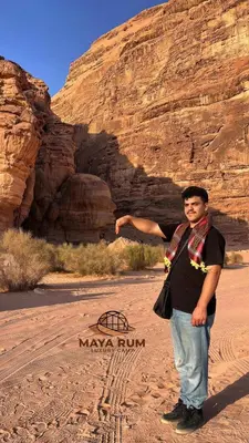 a man standing in the desert in front of a mountain at MAYA RUM LUXURY CAMP & Jeep Tours in Disah
