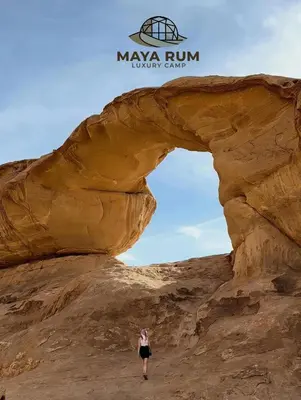 a woman standing in front of an arch in the desert at MAYA RUM LUXURY CAMP & Jeep Tours in Disah